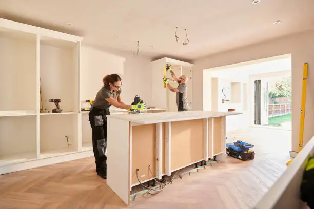 A man and woman working on a kitchen island.