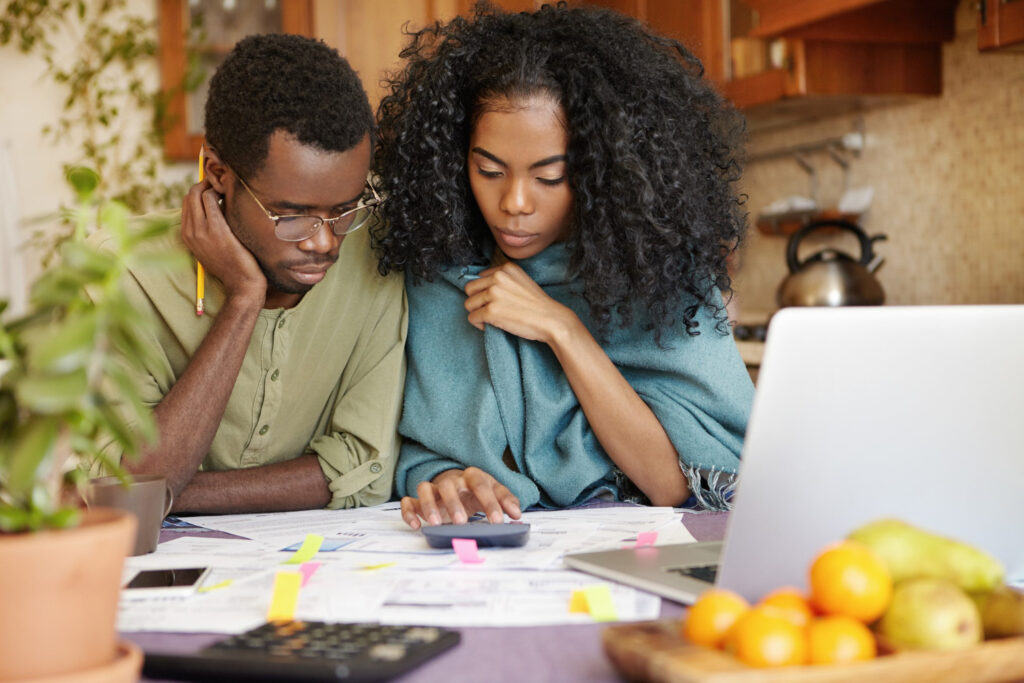 couple sitting at table, typing on a calculator, and budgeting for a home renovation