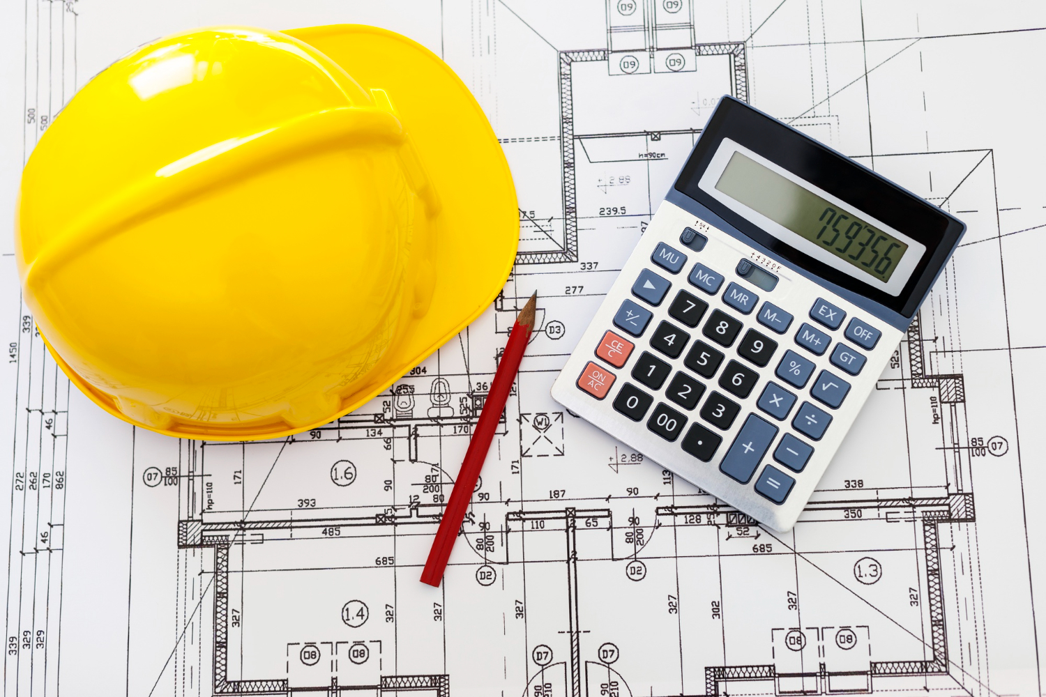 Blueprint with a calculator, tape measure, notebook, and construction cost estimate spread across a table.